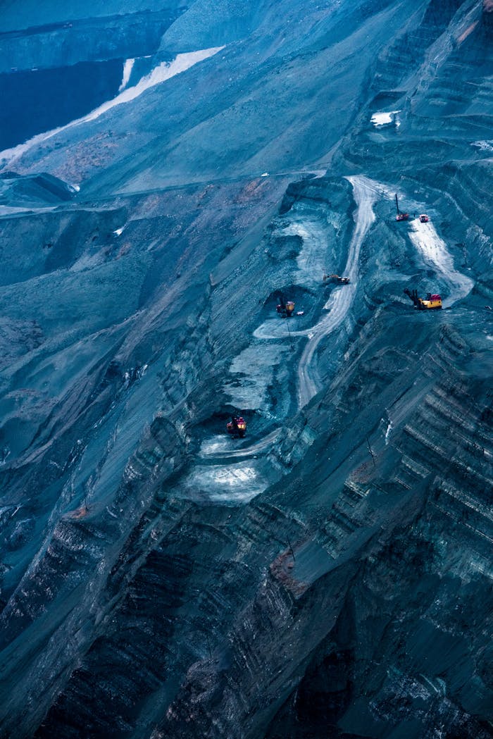 Aerial image showcasing a vast open-pit mine during winter with visible excavators and snow patches.